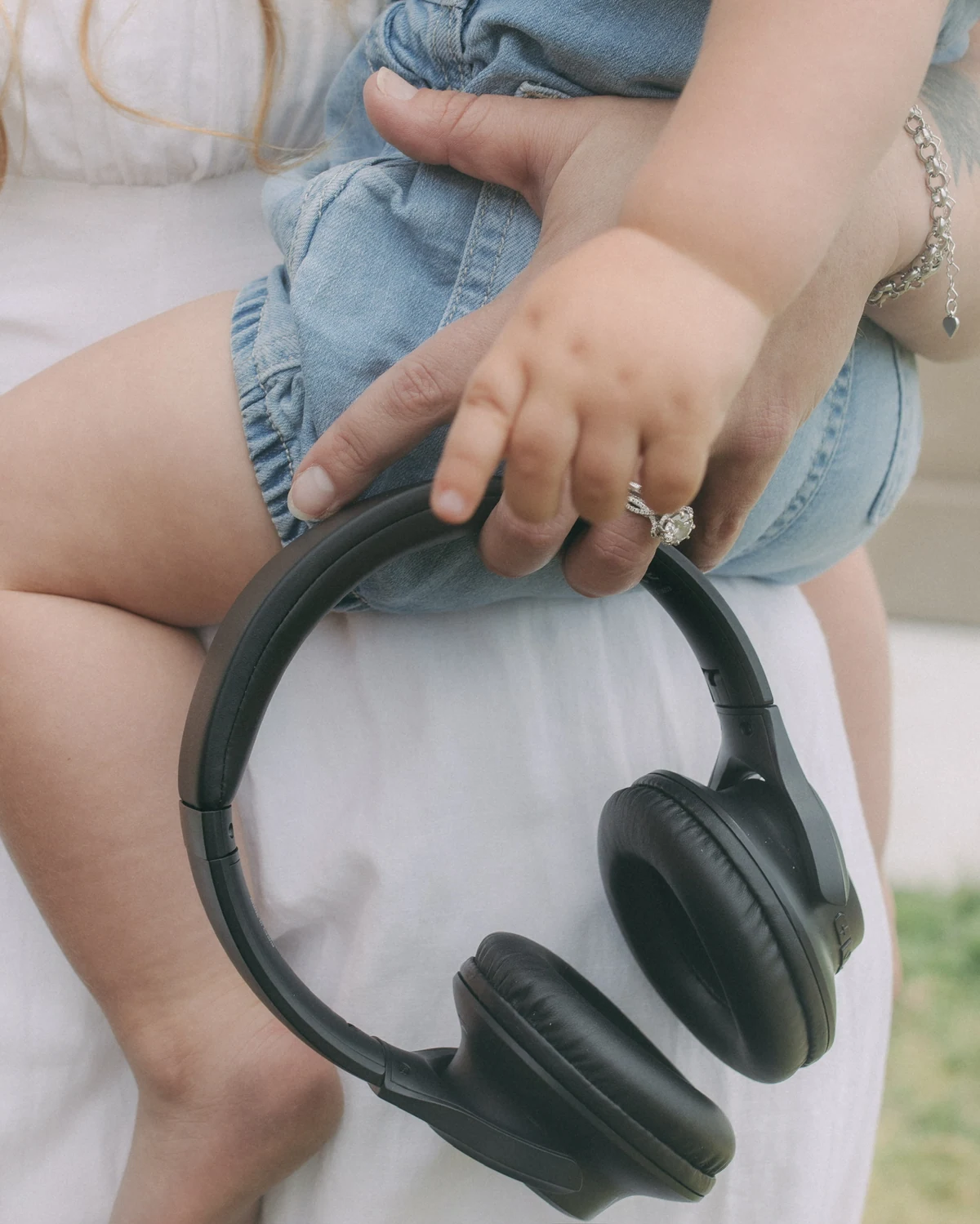Headphones resting on a mother's lap as her child reaches across.