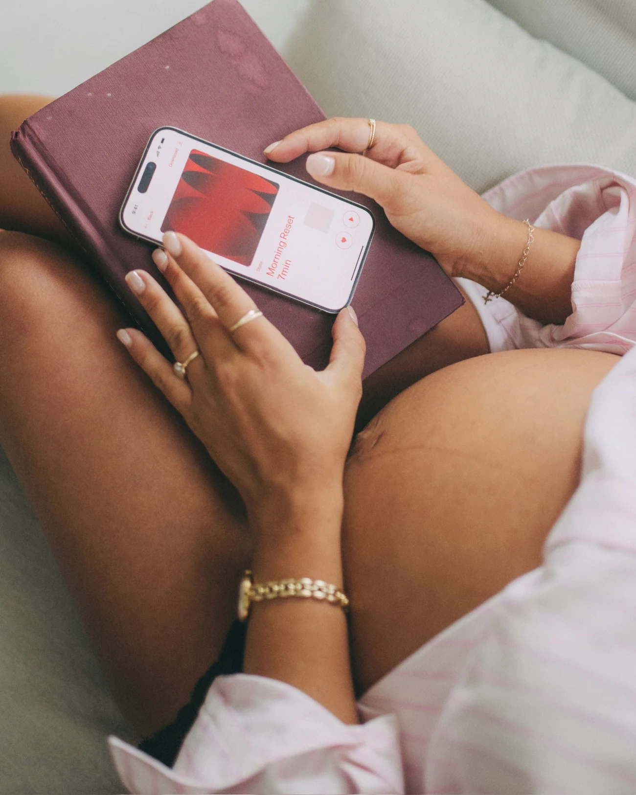 Hands holding a phone with an MTHR practice open, resting on a notebook.